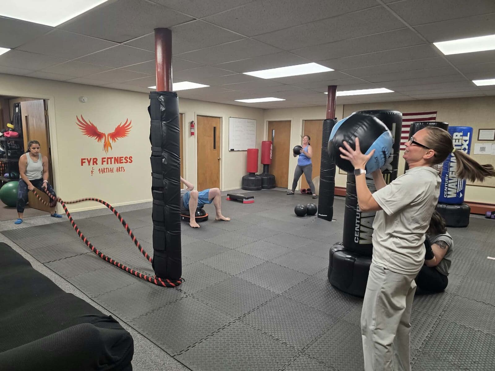 Members working with medicine balls and heavy bags during class